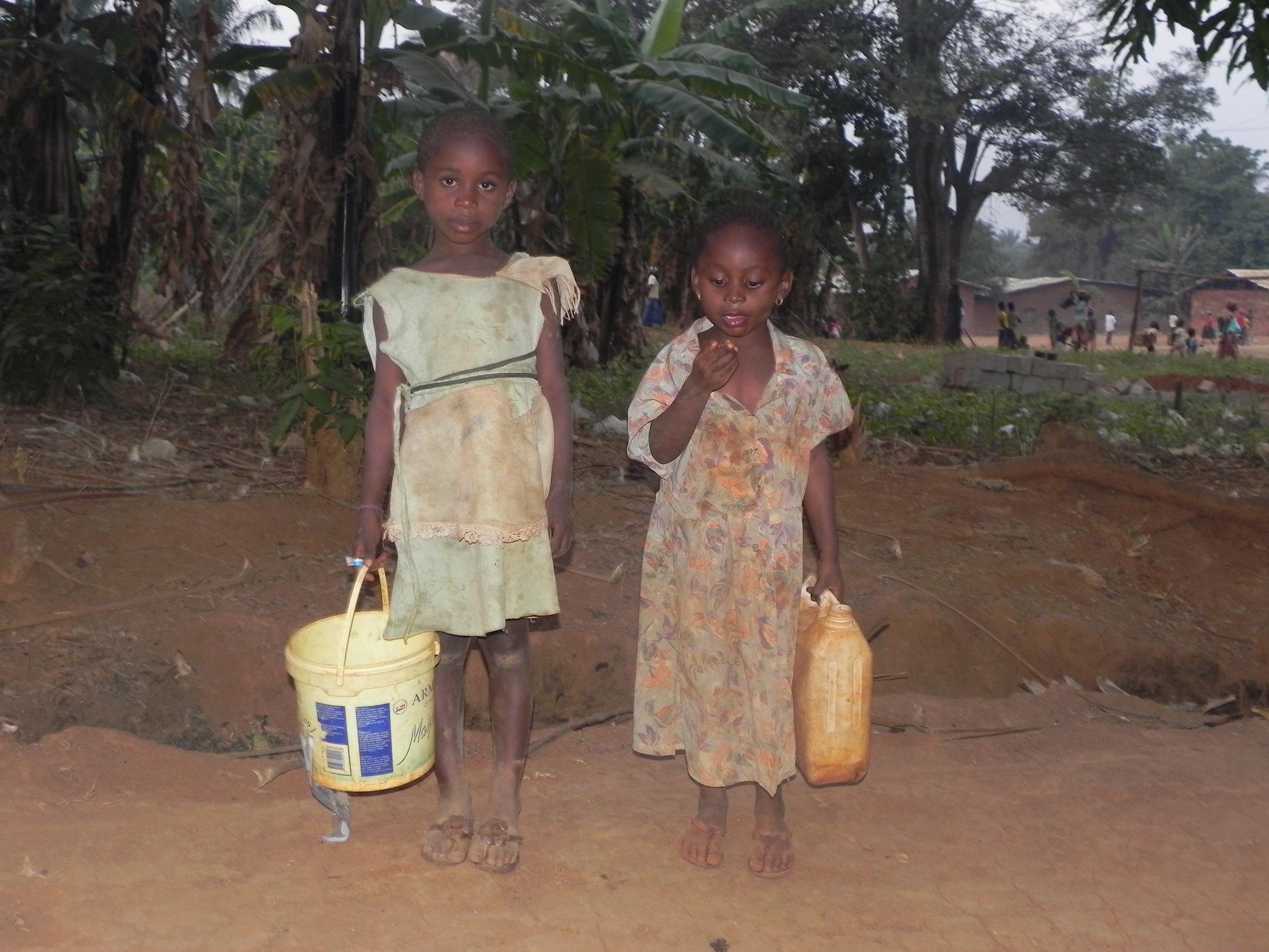 Two girls standing outside with their buckets of water showcasing the importance of clean water for africa.