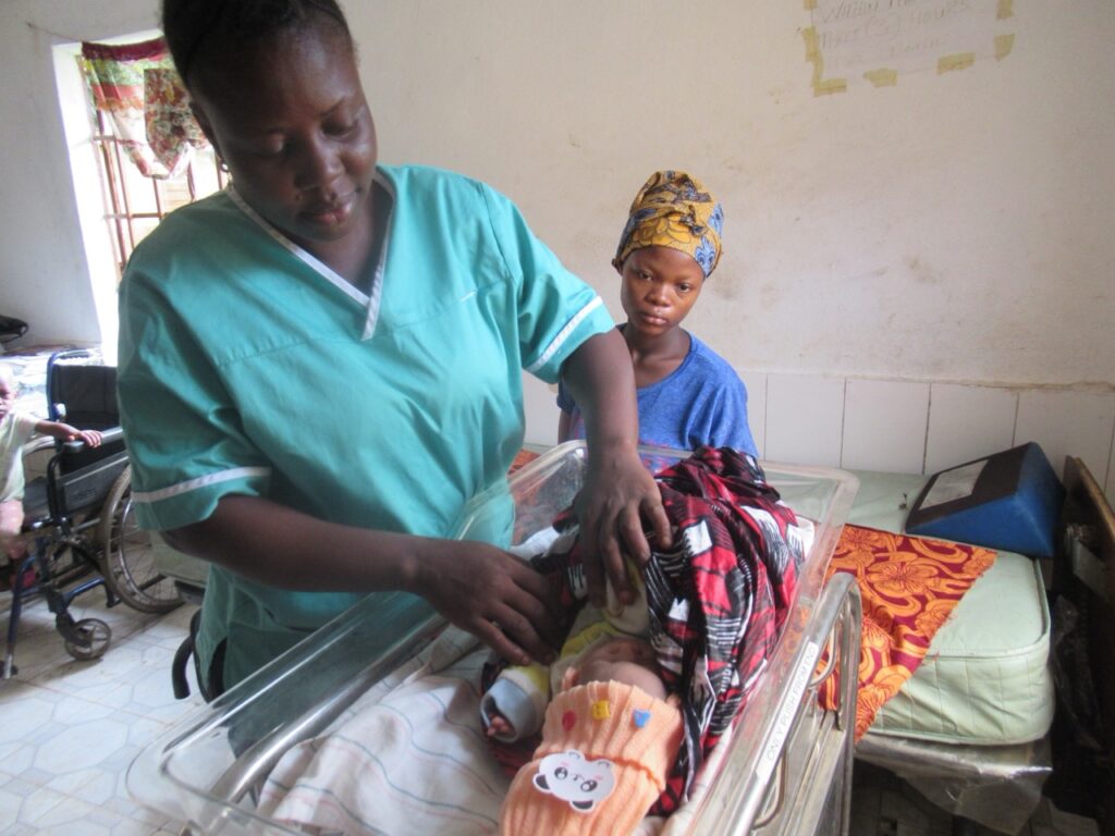 At the Mokoba Health Center, Nurse Fati Jabbie provides dedicated care for a newborn infant as the mother looks on.