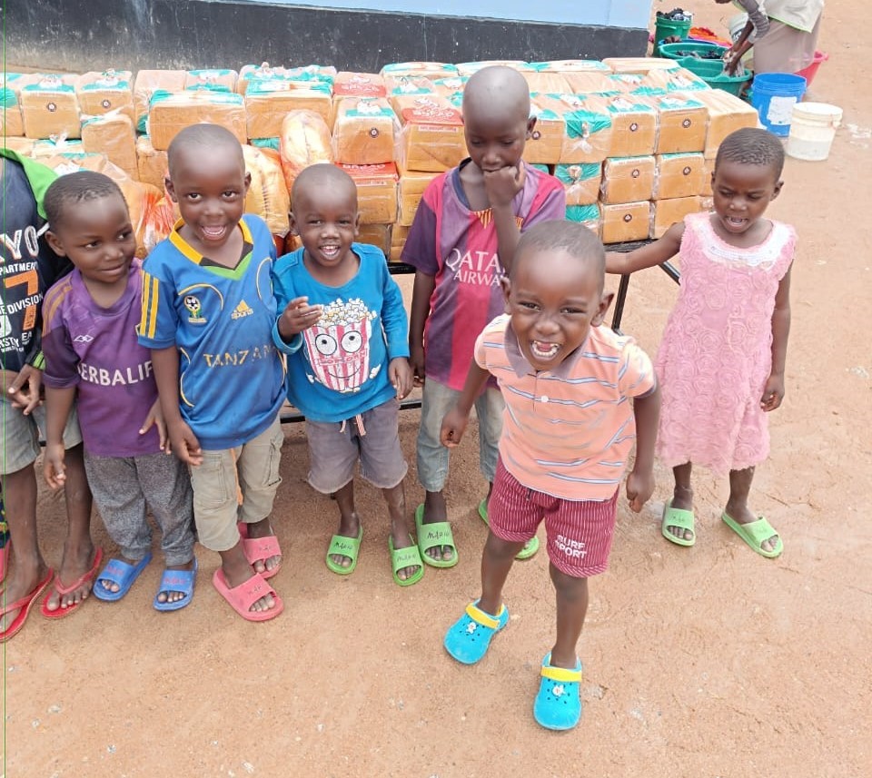 Happy young children at the Watoto Wa Africa Orphanage smile in front of a large donation of sliced bread.