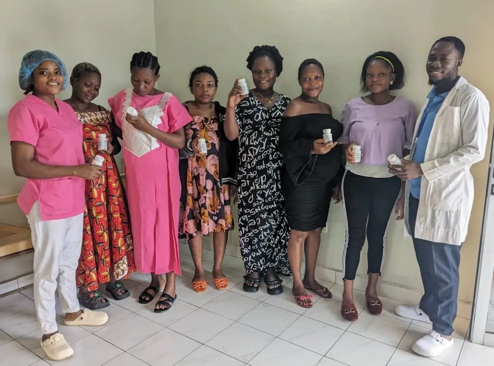 Pregnant women and healthcare staff holding prenatal vitamins.