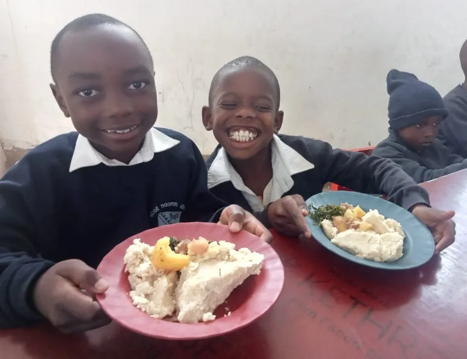 Schoolboys in uniform enjoying a meal at their desks in Kenya.