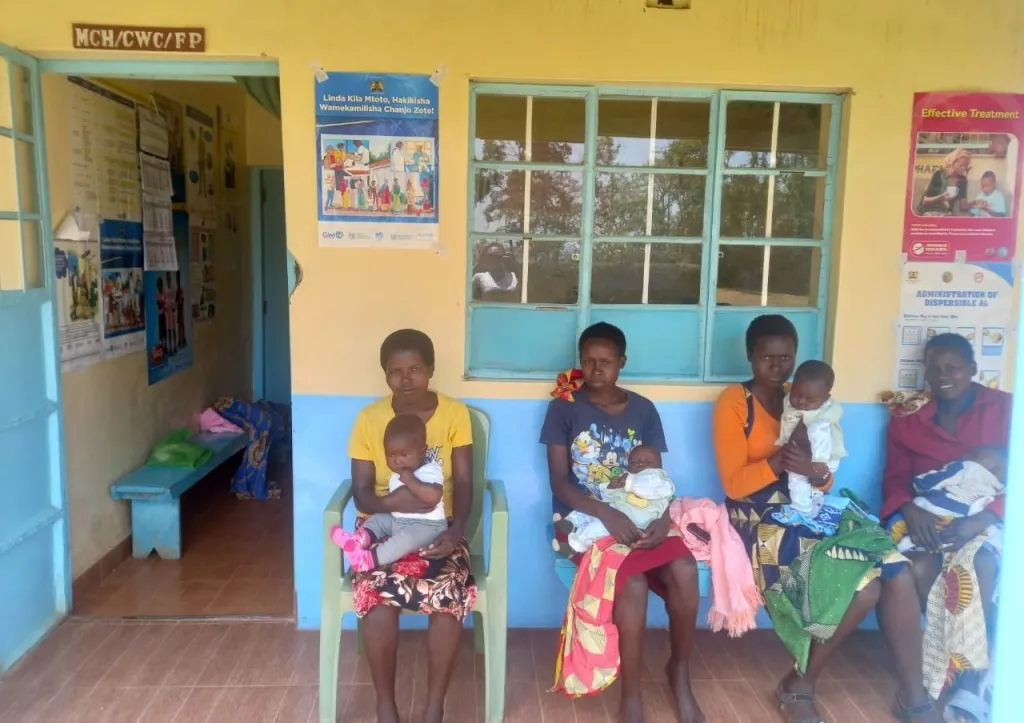 Mothers with infants waiting for care outside a rural health clinic in Kenya.