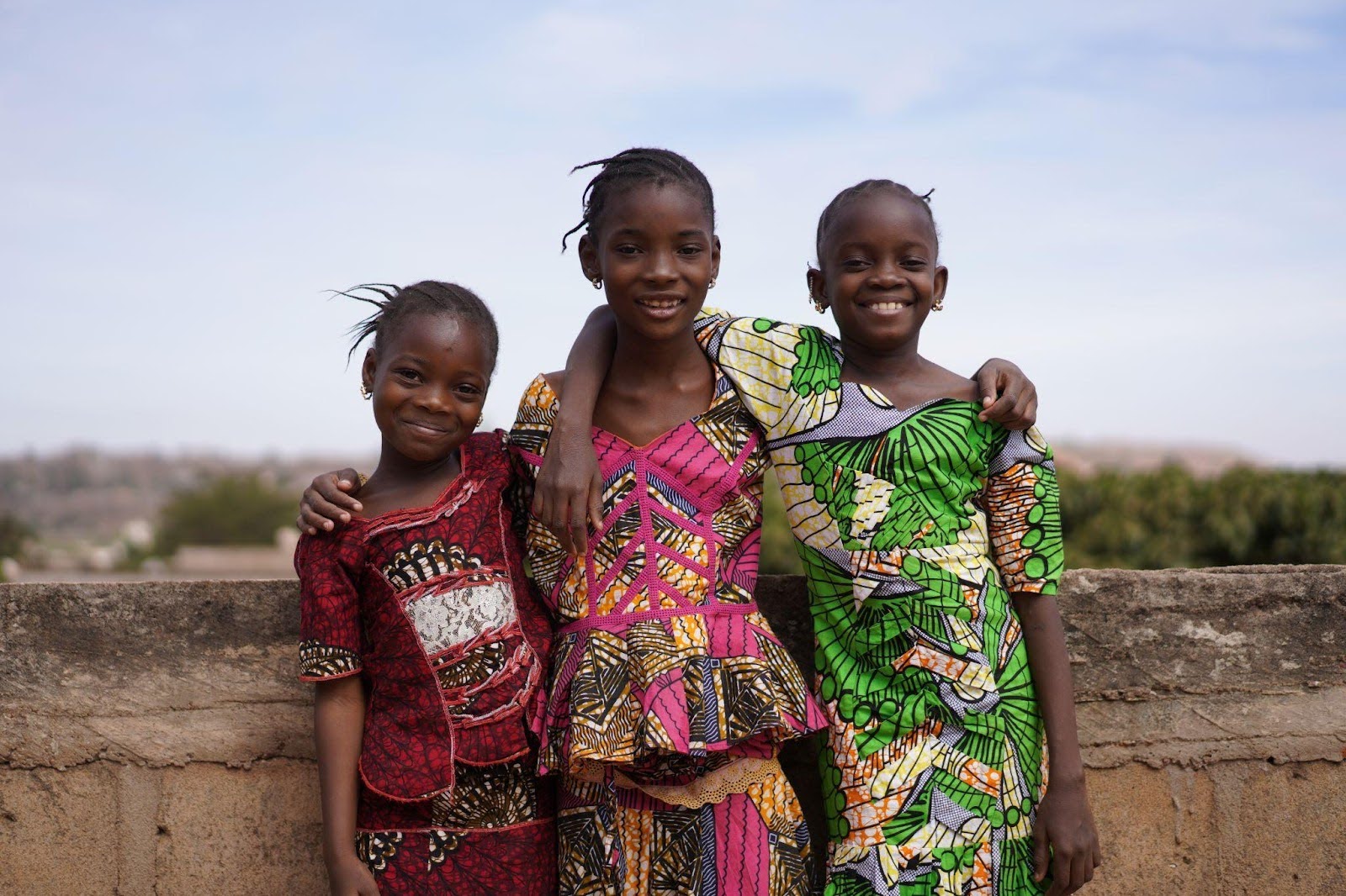Three young African girls smiling & posing for picture
