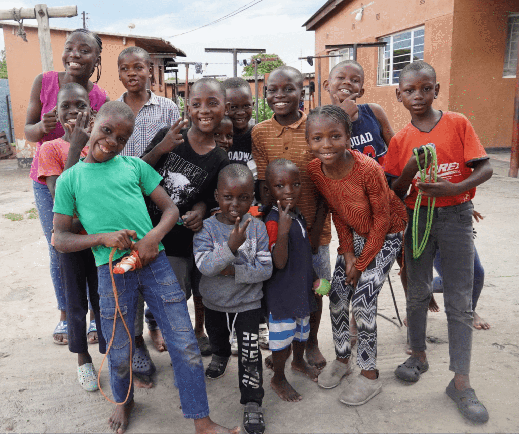 A group of happy, smiling school-aged children in an African community.