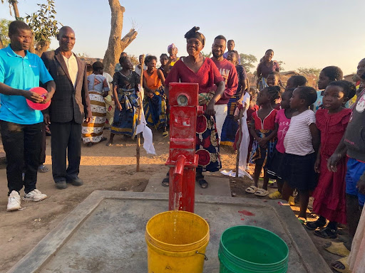 Villagers gather around a new borehole, celebrating access to clean water in Malawi.