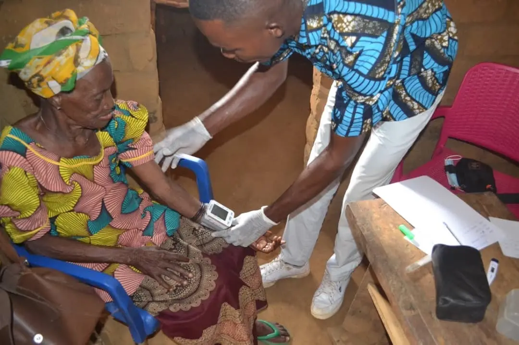 An elderly woman in the Congo receives a blood pressure check from a health worker.
